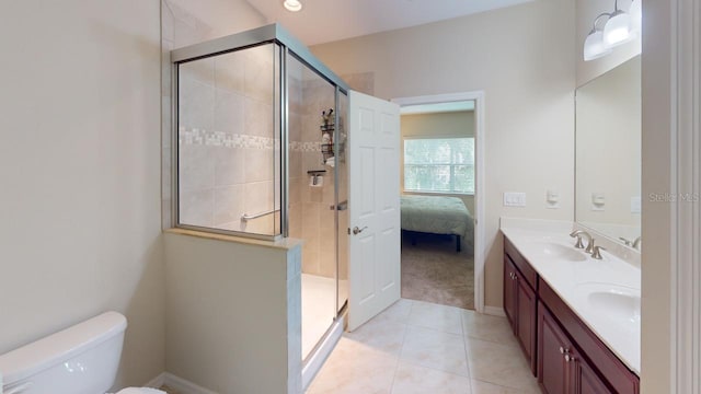 bathroom with a shower with door, toilet, vanity, and tile patterned floors