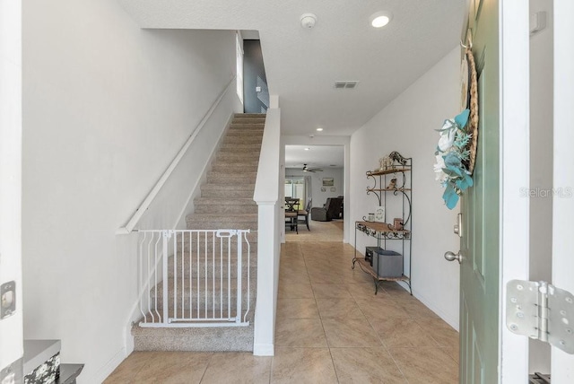 staircase with ceiling fan and tile patterned floors