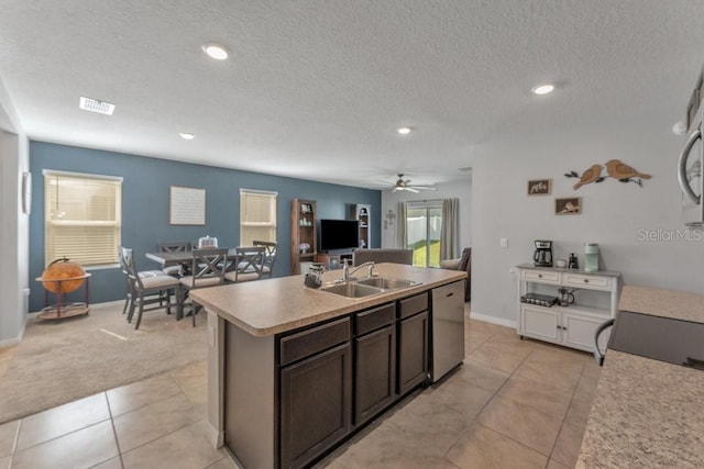 kitchen with dark brown cabinets, sink, a center island with sink, ceiling fan, and stainless steel dishwasher