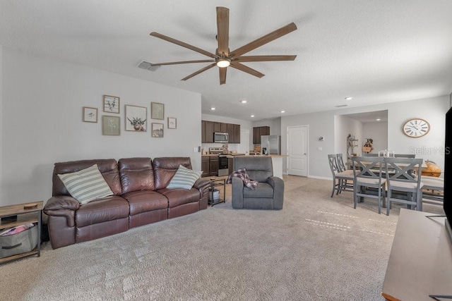 carpeted living room with ceiling fan and a textured ceiling