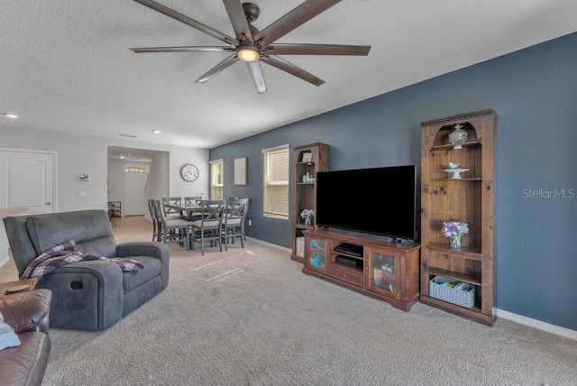 carpeted living room featuring ceiling fan and a textured ceiling