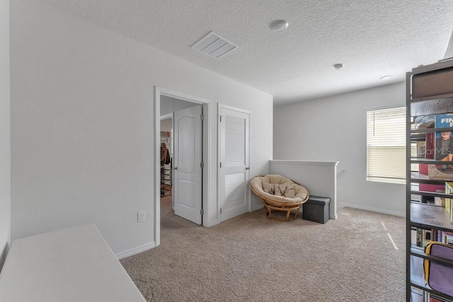 living area featuring a textured ceiling and light carpet