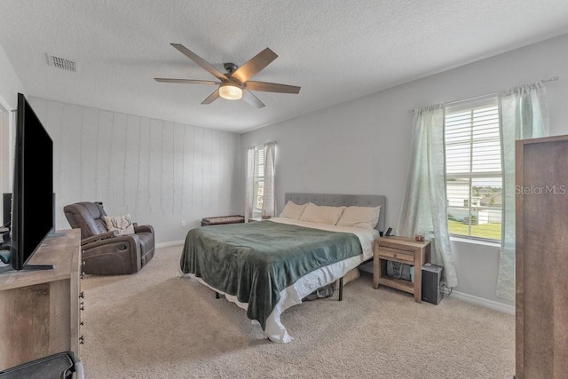 bedroom with ceiling fan, a textured ceiling, and light carpet