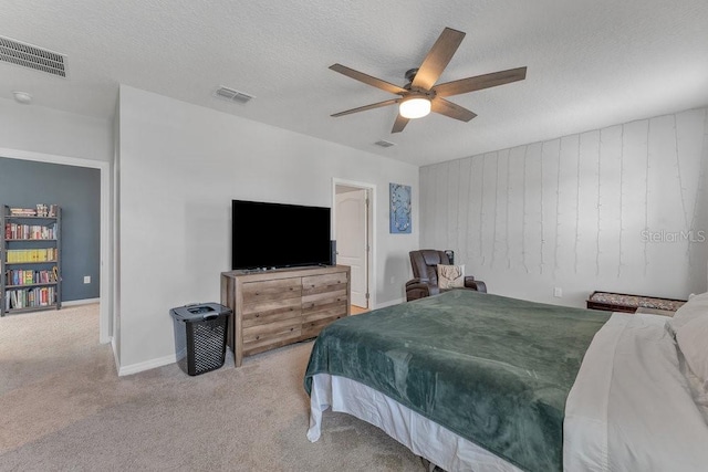 bedroom with ceiling fan, light colored carpet, and a textured ceiling