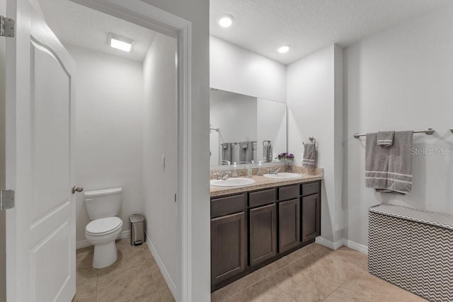 bathroom featuring tile patterned flooring, a textured ceiling, vanity, and toilet