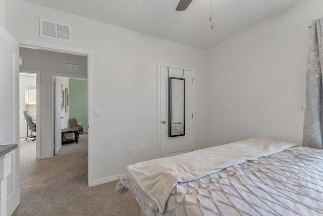 bedroom featuring a textured ceiling, ceiling fan, and light colored carpet