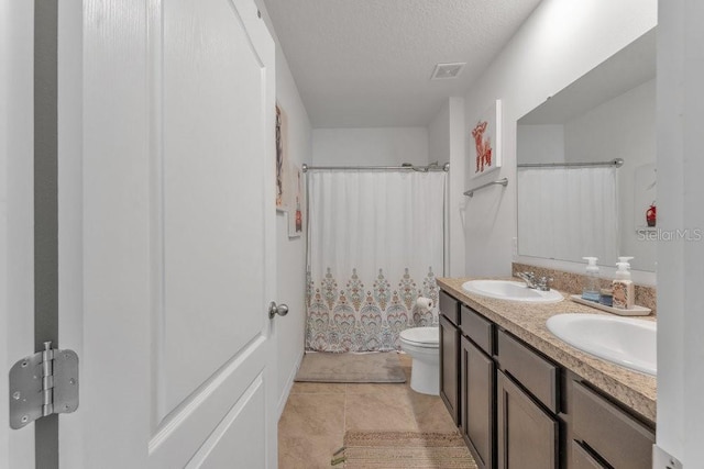 bathroom with curtained shower, vanity, a textured ceiling, toilet, and tile patterned floors