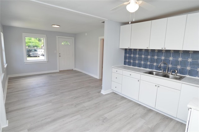 kitchen featuring ceiling fan, sink, white cabinetry, light hardwood / wood-style floors, and decorative backsplash