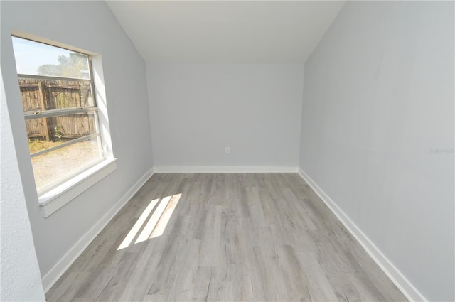 empty room with vaulted ceiling, light hardwood / wood-style floors, and plenty of natural light