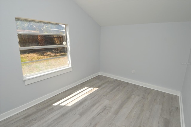 spare room featuring lofted ceiling and light hardwood / wood-style floors