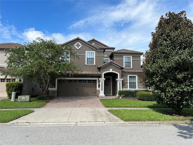 view of front of property with a tiled roof, a garage, decorative driveway, and stucco siding