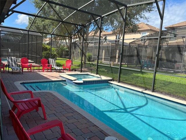 view of swimming pool featuring glass enclosure, an in ground hot tub, and a patio area