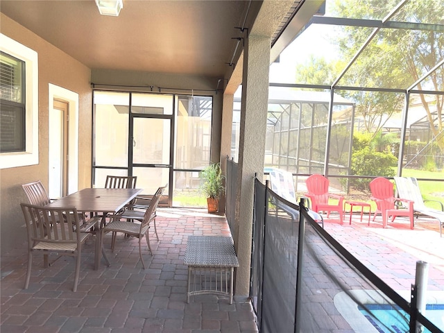 view of patio with outdoor dining area and glass enclosure