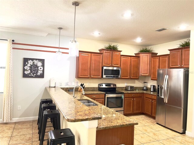 kitchen featuring kitchen peninsula, a breakfast bar area, stainless steel appliances, decorative light fixtures, and sink