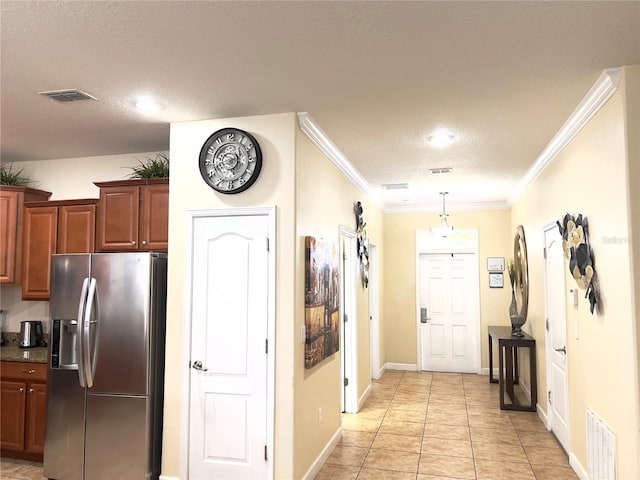 hall with visible vents, a textured ceiling, ornamental molding, and light tile patterned flooring