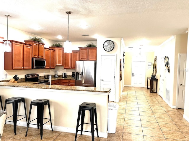 kitchen with appliances with stainless steel finishes, kitchen peninsula, a breakfast bar, and decorative light fixtures