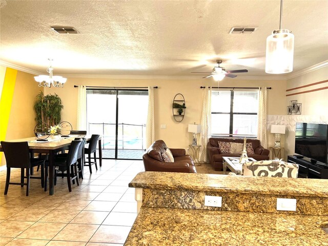 tiled living room with a textured ceiling, ceiling fan with notable chandelier, and crown molding