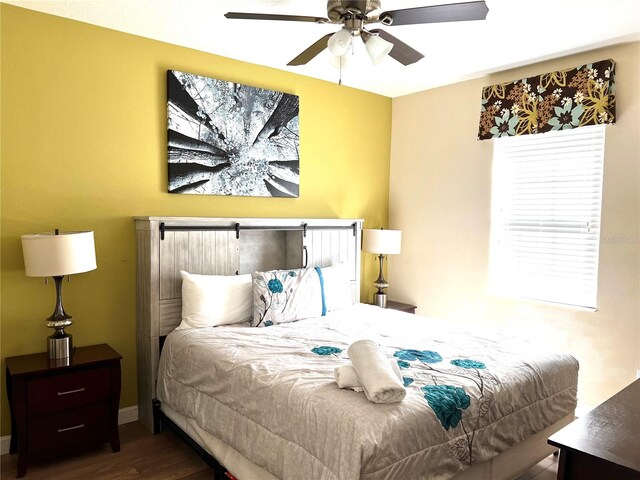 bedroom featuring wood-type flooring, ceiling fan, and a barn door