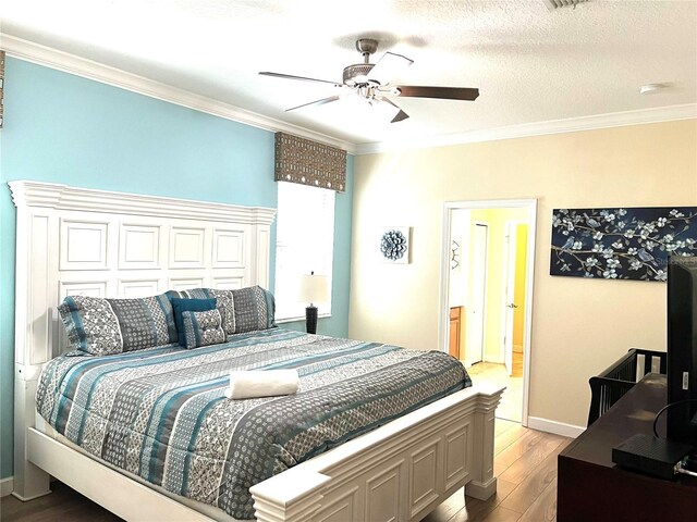bedroom featuring baseboards, ornamental molding, light wood-type flooring, a ceiling fan, and a textured ceiling