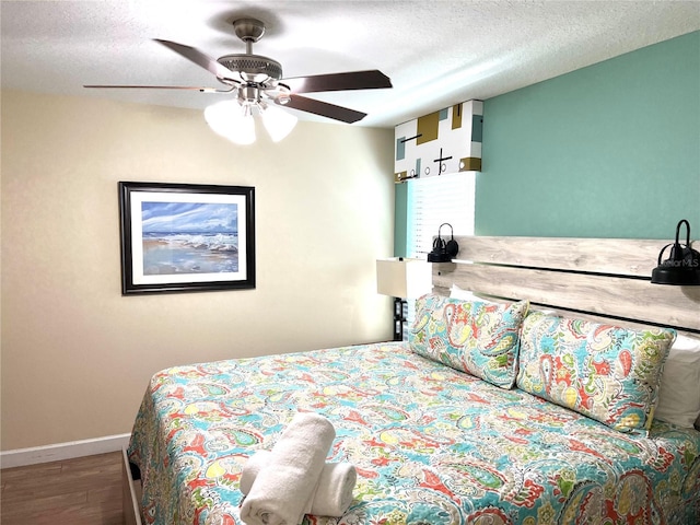 bedroom with a textured ceiling, wood finished floors, baseboards, and a ceiling fan