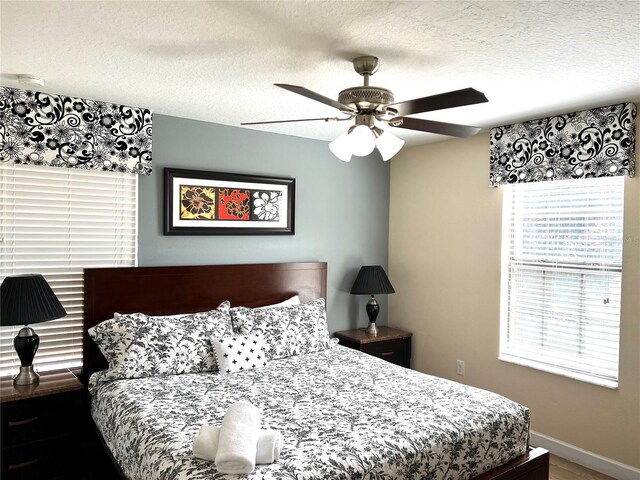 bedroom with a textured ceiling, ceiling fan, and hardwood / wood-style flooring