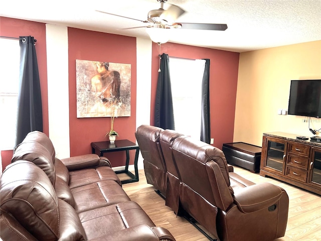 living room with light wood-type flooring, ceiling fan, a wealth of natural light, and a textured ceiling