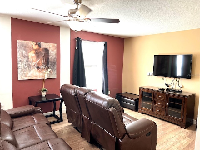 living area featuring light wood-style floors, baseboards, a ceiling fan, and a textured ceiling