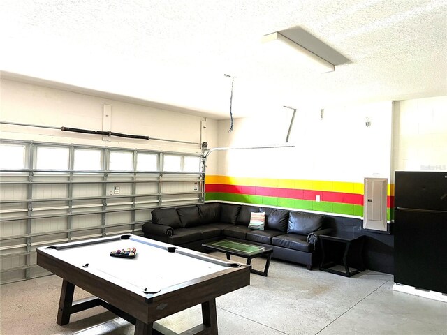 game room with a textured ceiling, concrete flooring, and electric panel