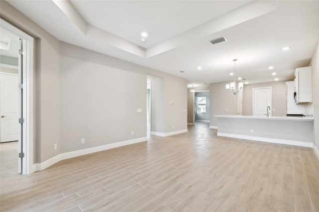 unfurnished living room featuring an inviting chandelier and light wood-type flooring