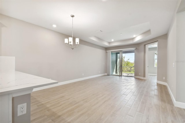 interior space featuring light hardwood / wood-style floors, a chandelier, and a tray ceiling