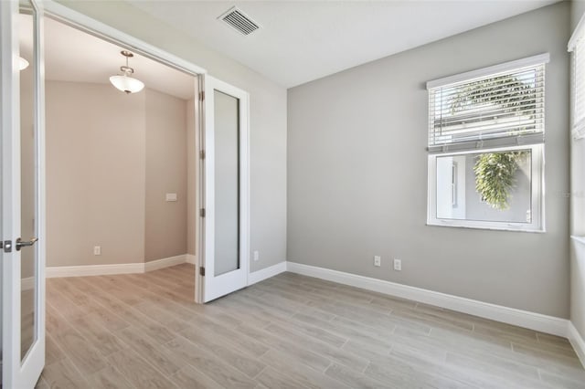 unfurnished bedroom featuring french doors and light hardwood / wood-style flooring