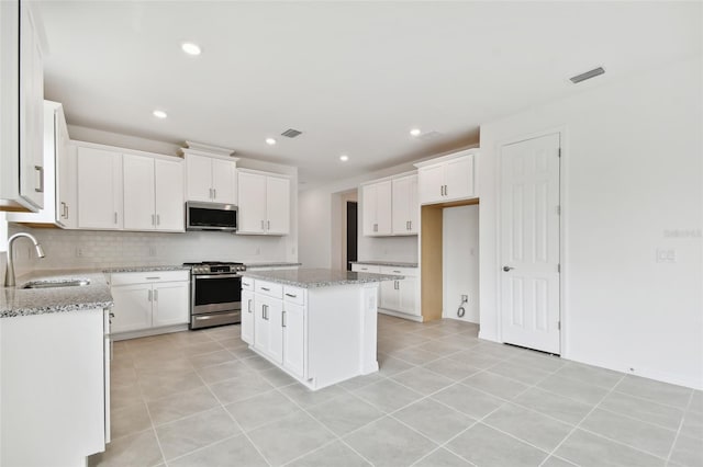 kitchen with white cabinets, appliances with stainless steel finishes, sink, and a center island