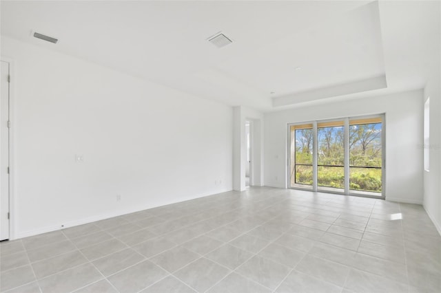 tiled spare room with a tray ceiling