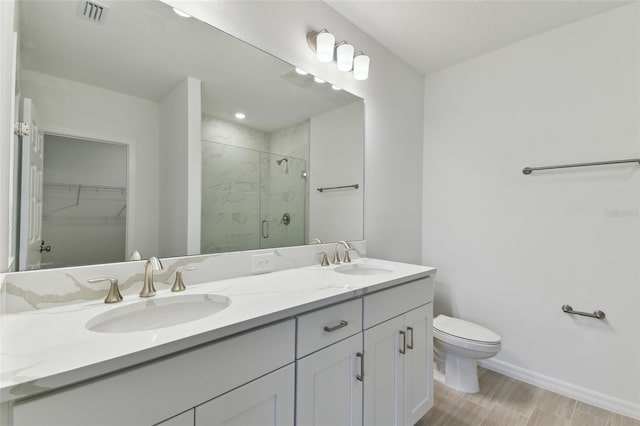 bathroom featuring a shower with door, vanity, wood-type flooring, and toilet