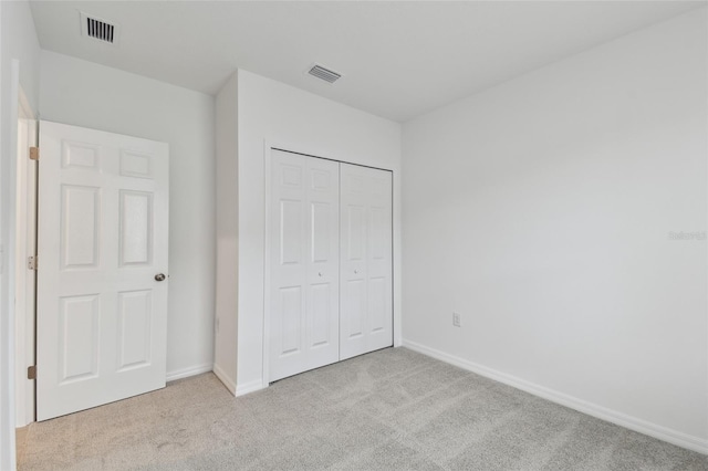 unfurnished bedroom with light colored carpet and a closet