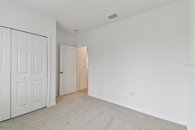 unfurnished bedroom with light colored carpet and a closet