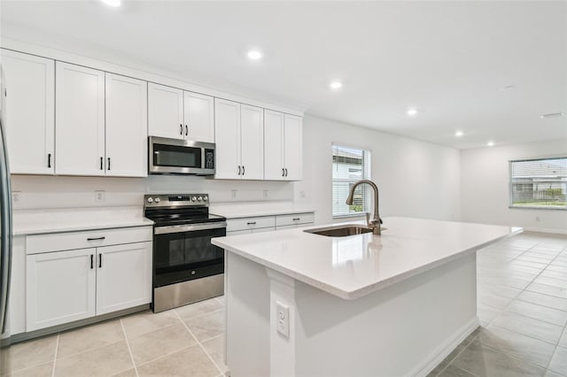 kitchen with white cabinetry, appliances with stainless steel finishes, sink, and a center island with sink