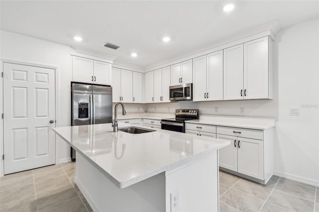 kitchen featuring sink, appliances with stainless steel finishes, white cabinetry, light stone counters, and a center island with sink