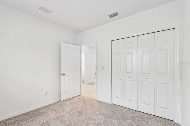 unfurnished bedroom featuring light carpet and a closet