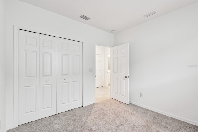 unfurnished bedroom featuring light colored carpet and a closet