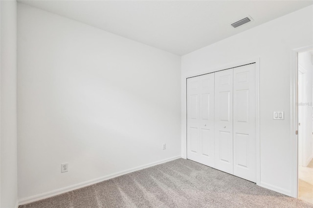 unfurnished bedroom featuring light colored carpet and a closet