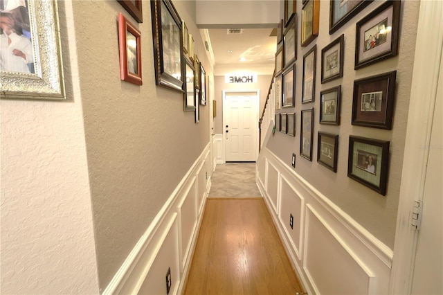 5002 Tideview Cir Unit 3, Orlando, FL 32819 - hall with visible vents, a textured wall, a decorative wall, light wood-style floors, and a wainscoted wall