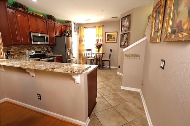 5002 Tideview Cir Unit 3, Orlando, FL 32819 - kitchen with light stone countertops, baseboards, a peninsula, a breakfast bar, and stainless steel appliances