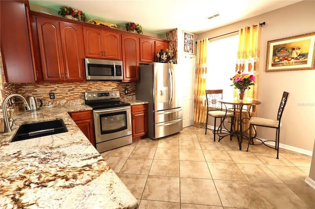 5002 Tideview Cir Unit 3, Orlando, FL 32819 - kitchen with tasteful backsplash, light stone counters, a sink, appliances with stainless steel finishes, and light tile patterned floors