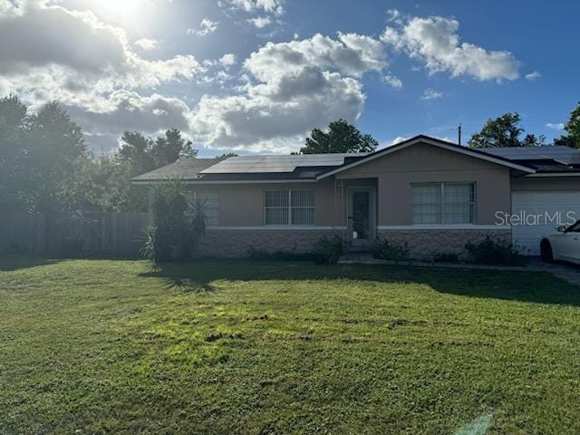 ranch-style house featuring a front lawn and solar panels