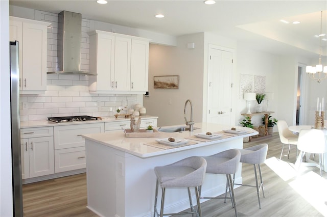 kitchen with white cabinetry, sink, stainless steel appliances, and wall chimney exhaust hood