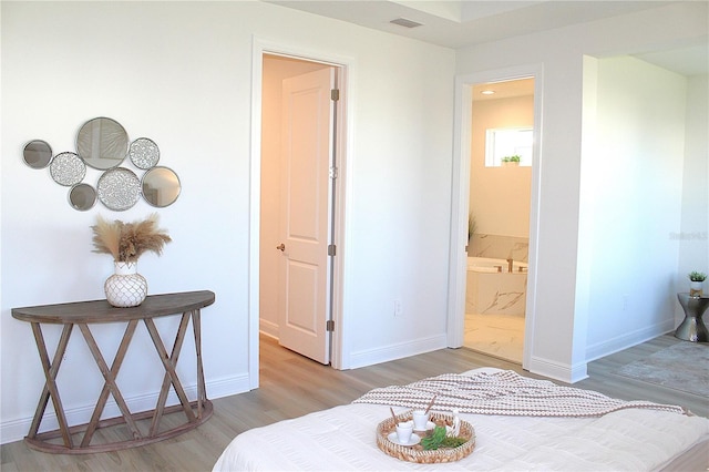 bedroom with connected bathroom and hardwood / wood-style floors