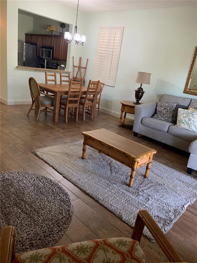 living area with baseboards, hardwood / wood-style flooring, and a chandelier