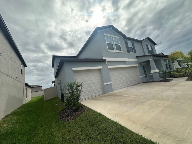 view of side of property with fence, concrete driveway, stucco siding, a lawn, and a garage