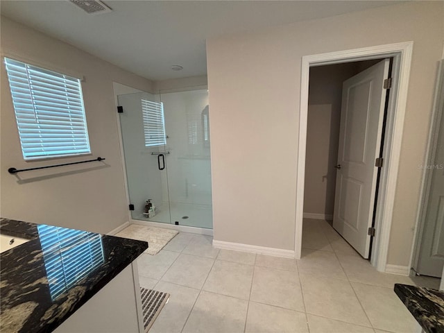 bathroom with tile patterned flooring, visible vents, a shower stall, and baseboards